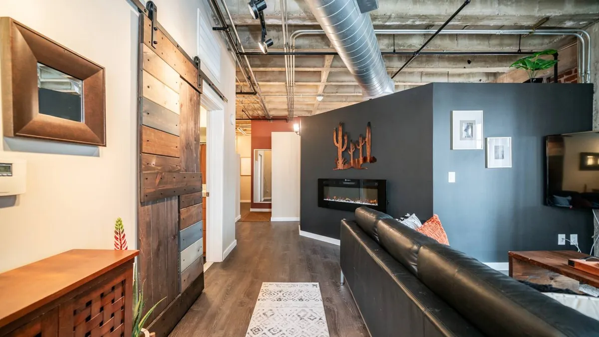 A welcoming living area with a stylish modern fireplace, black accent wall, and inviting sofa. The room’s layout suggests relaxation and comfort, ideal for unwinding after a day of exploration.