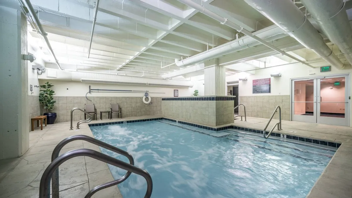 This image features a serene indoor swimming pool area, complete with stainless steel railings, tile flooring, and lush indoor plants. The tranquil setting is conducive to both social gatherings and solitary reflection, with the pool as the focal point.