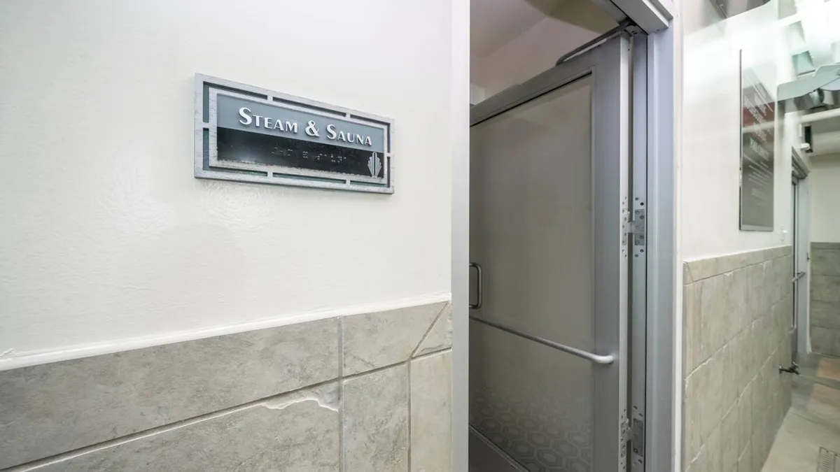 A tranquil area marked by a 'Steam & Sauna' sign and a glass door, suggesting access to wellness amenities. The space feels serene and exclusive, emphasizing relaxation and self-care.